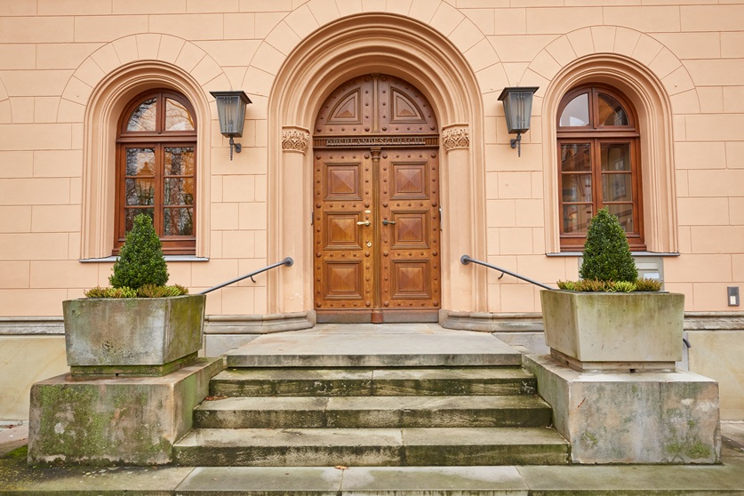 Historische, braune Eingangstür des Oberlandesgerichts Celle mit zwei Türklingen und goldenen Beschlägen